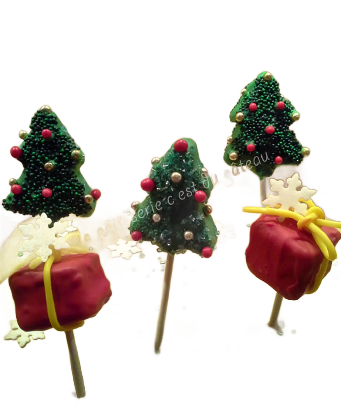 Cake pops de Noël en forme de sapins et de paquets cadeaux, avec des flocons blancs.