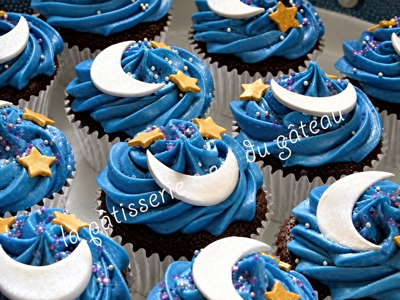 Cupcakes au glaçage bleu décorés de lunes blanches et d'étoiles dorées en pâte à sucre.