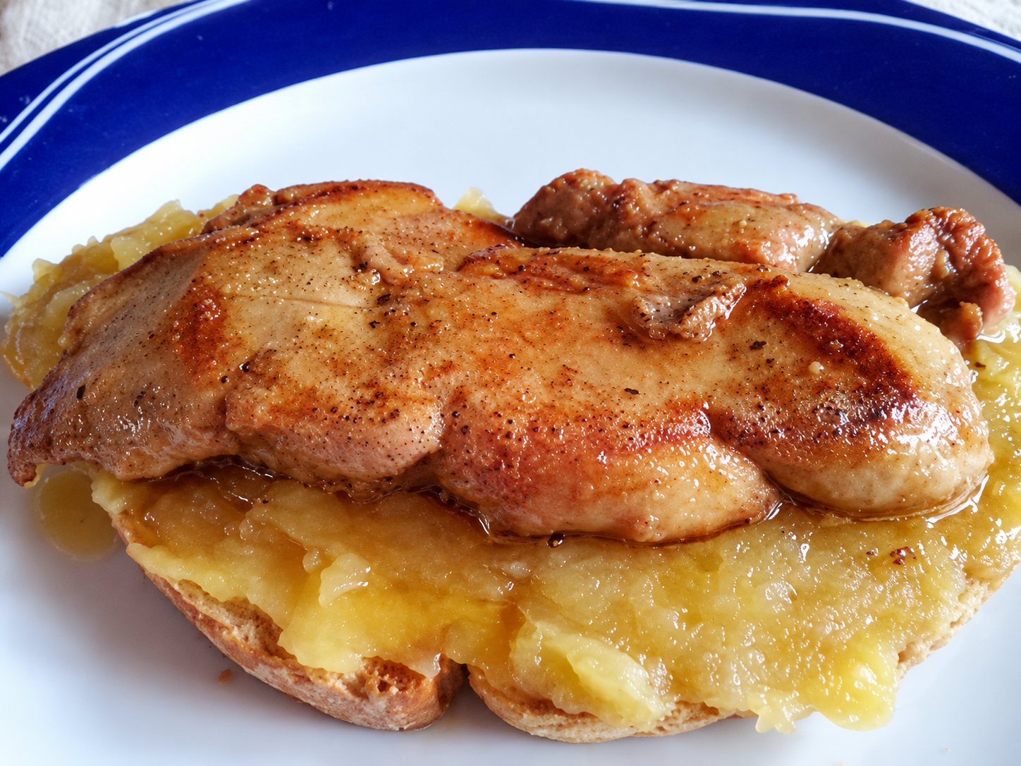 Escalope de foie gras poêlée posée sur une compotée de pommes.