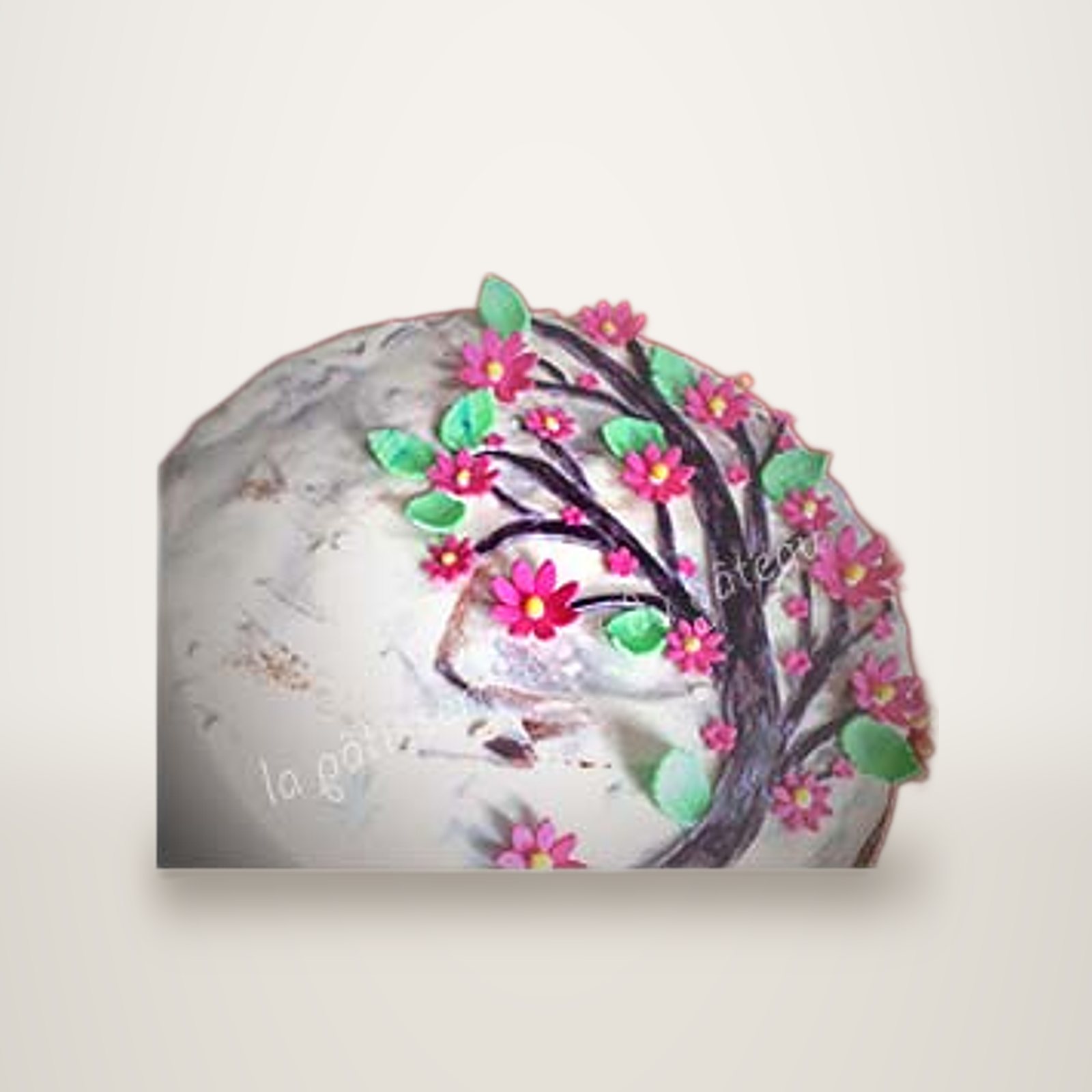 Gâteau décoré d'un arbre à fleurs roses et feuilles vertes en pâte à sucre.