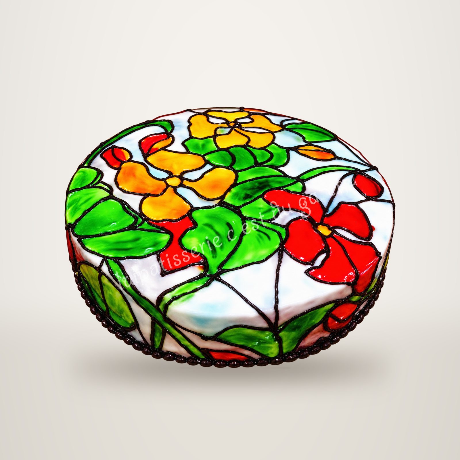 Gâteau peint à la main, effet vitrail, avec de grandes fleurs colorées.