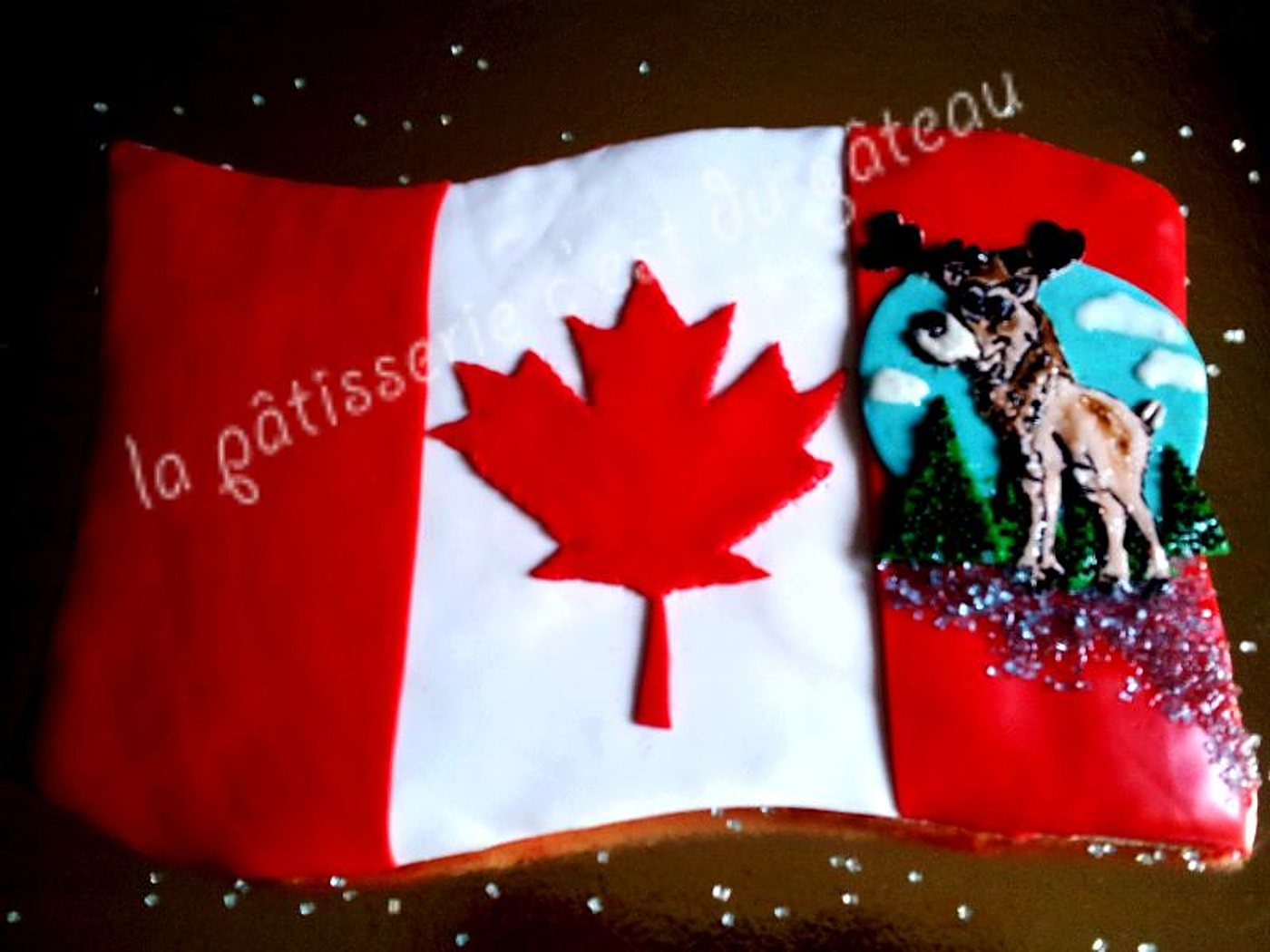 Gâteau décoré d'un drapeau canadien, d'une feuille d'érable et d'un caribou en pâte à sucre.