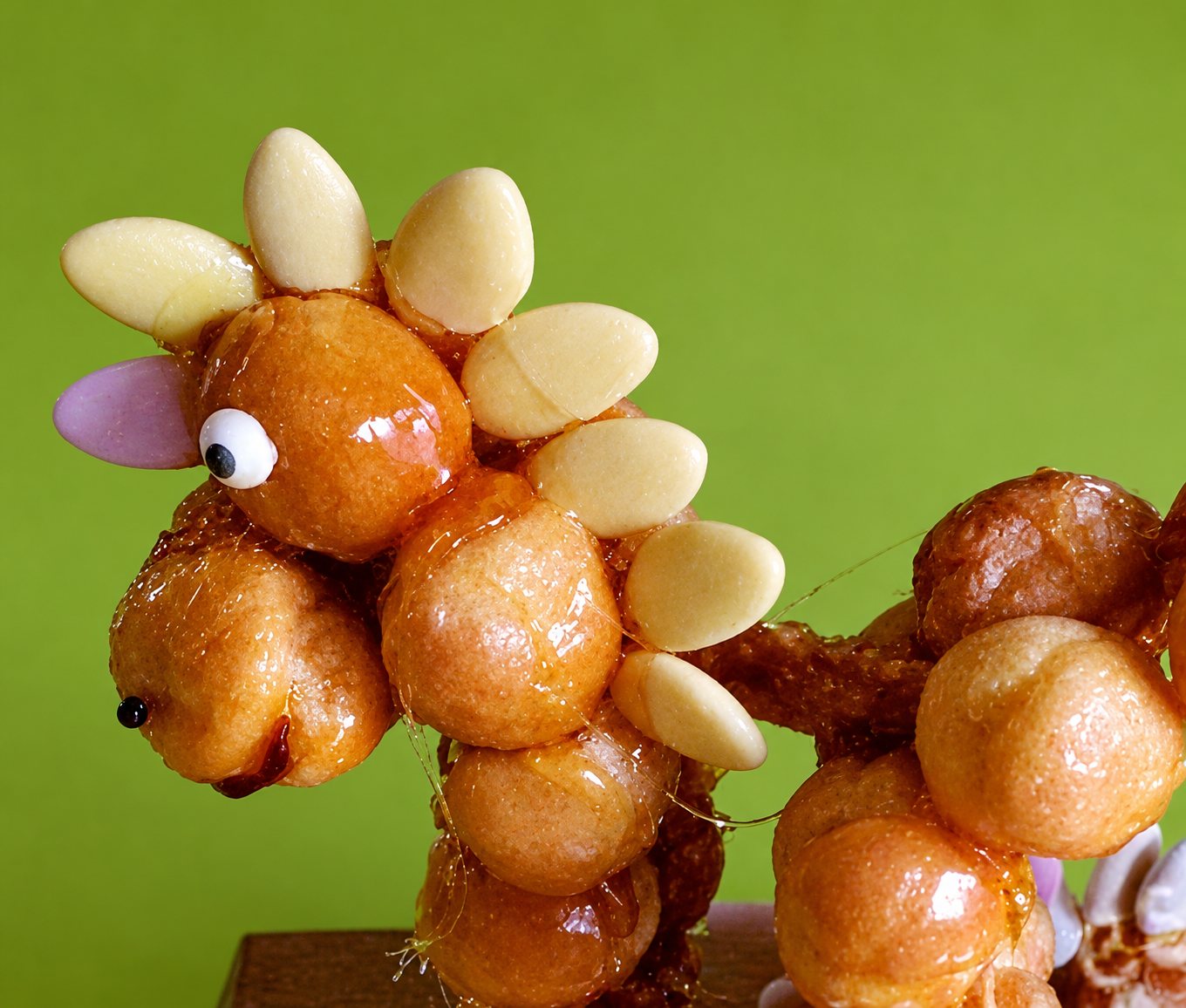Monstre de Loch Ness en choux caramélisés, décoré d'amandes et d'un œil comestible, devant un fond vert.